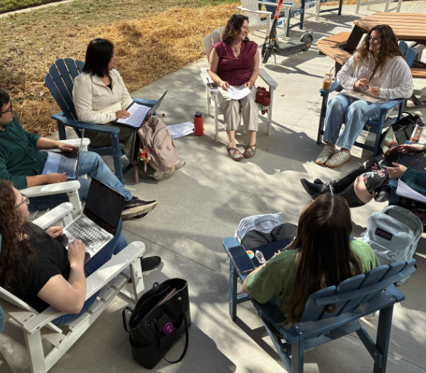 students and professor discussing course material in ampitheatre.